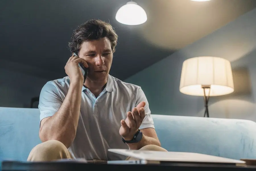 Homme au téléphone, assis sur son canapé