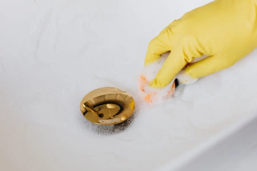 Main gantée près de l'évacuation d'un lavabo